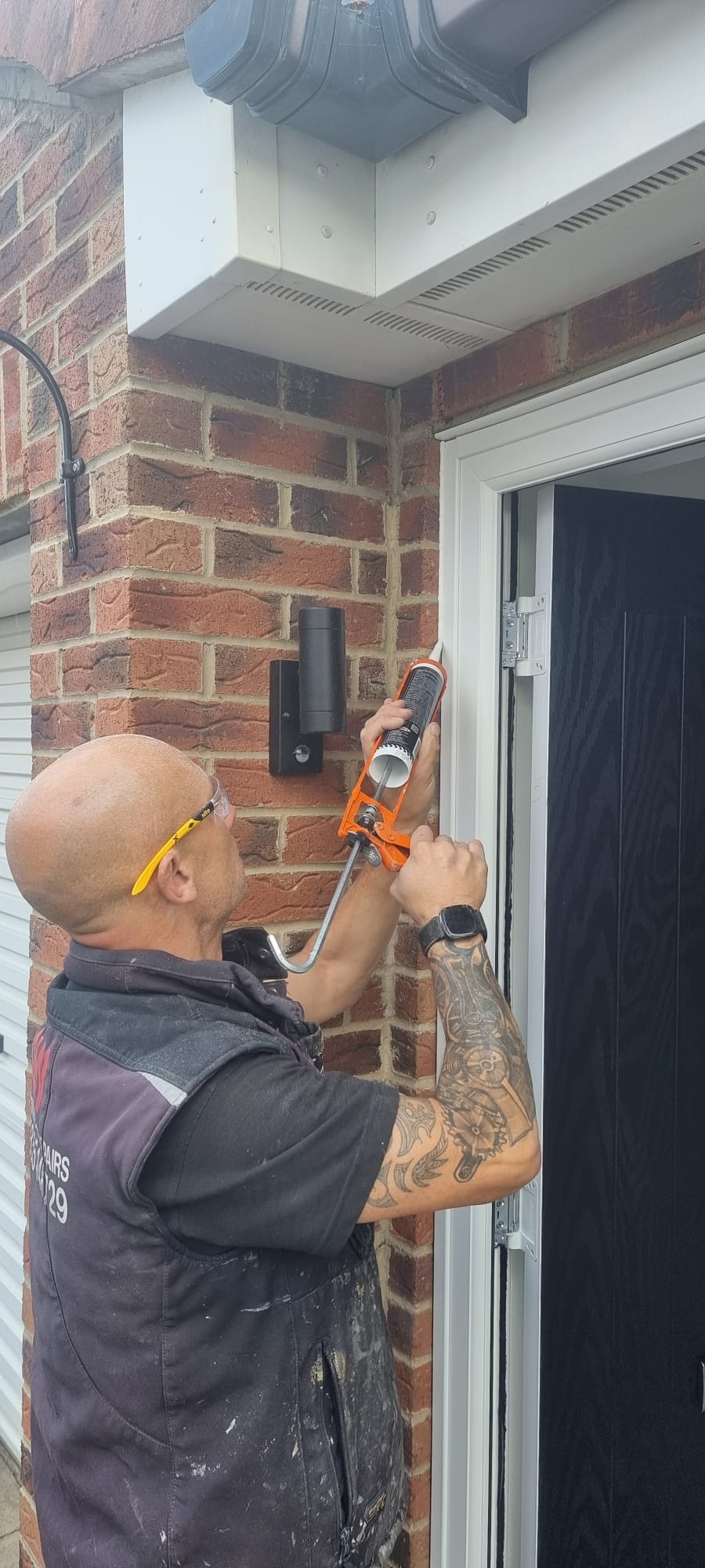 David Webb sealing a new door frame on a brick house in Hartlepool